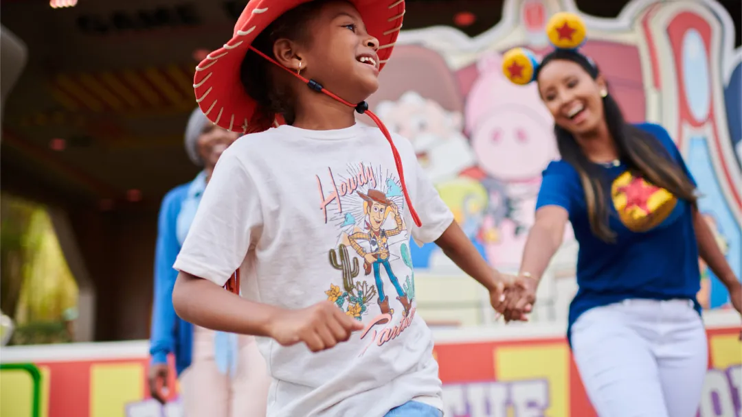 A mother holding her child's hand at a theme park.