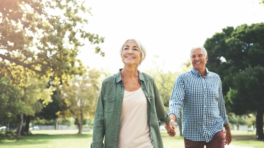 Elderly couple holding hands and walking in a park