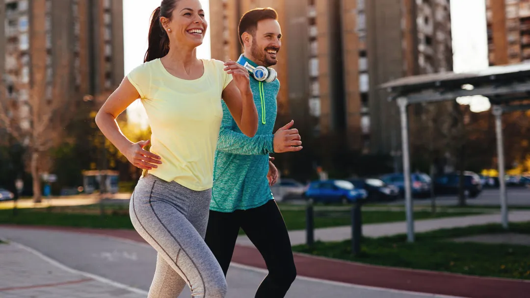 Couple running outside in the city during sunset.