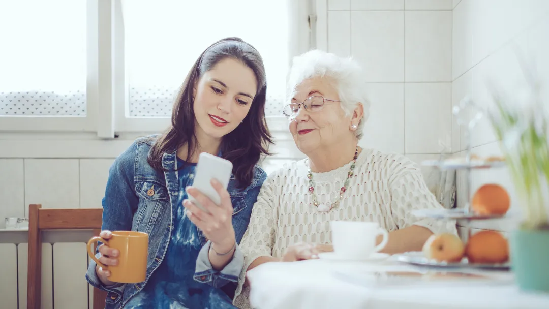 A young woman with an older women checking a cell phone