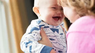 Baby laughing while his mother is holding him.