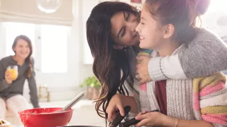 A woman hugging her daughter in the kitchen.