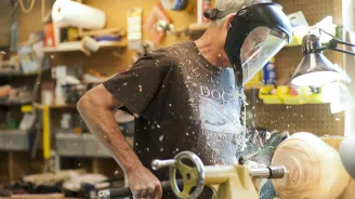 Mike Davis using a lathe to turn wood.