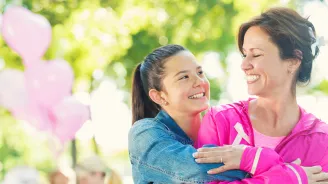 A daughter hugs her mother as they participate in a breast cancer walk.