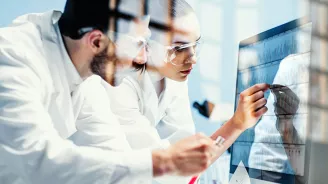 Two Physicians Look Over Test Results While in Scrubs