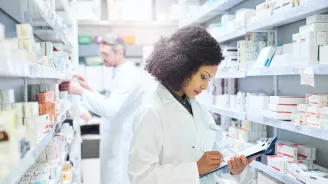 Female and male pharmacist working in an aisle in a pharmacy.