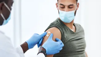 Man getting bandaged after a vaccine while wearing a mask.