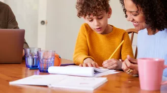 Mon and Son doing schoolwork at table