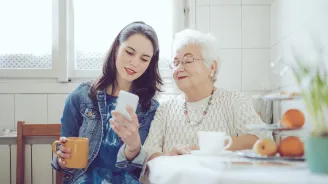 A young woman with an older women checking a cell phone