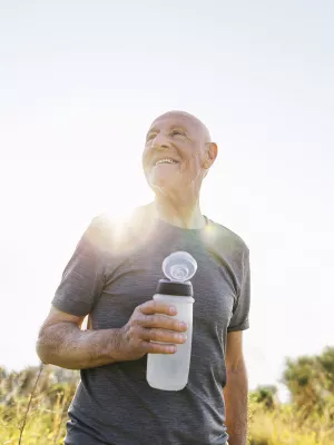 An older man takes a water break during a sunny outdoor hike
