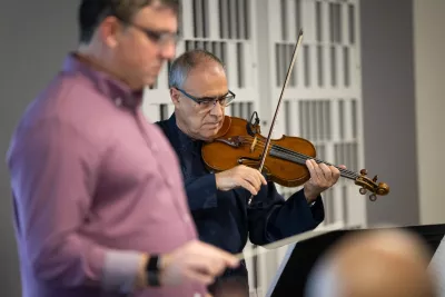Director Richard Hickam and principal violinist Paulo Pereira practice with the AdventHealth employee orchestra.
