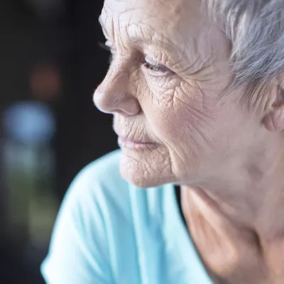 An elderly woman ponders, looking away from the camera.