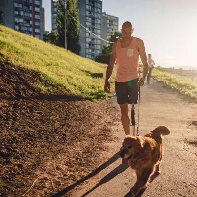 A young adult walking his dog on a sunny day