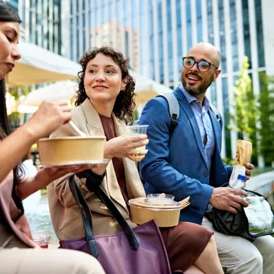 Three Colleagues Sit Outside Enjoying Lunch in the City.