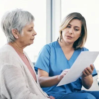 A Health Care Provider Goes Over Paperwork with a Patient at the Hospital.