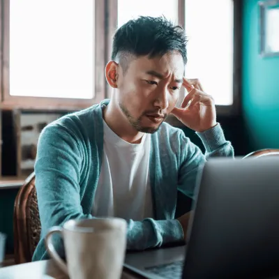 A Man Reads His Laptop at the Table