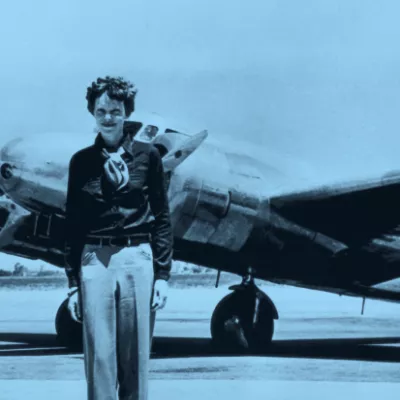 Amelia Earhart standing in from of a plane