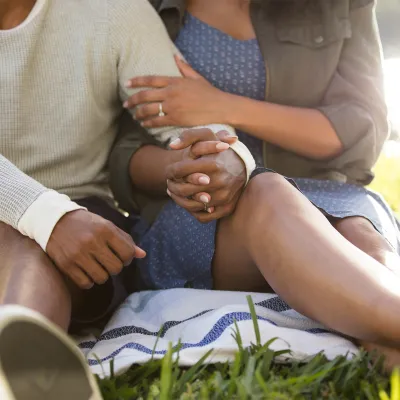 Couple holding hands on picnic blanket near the water