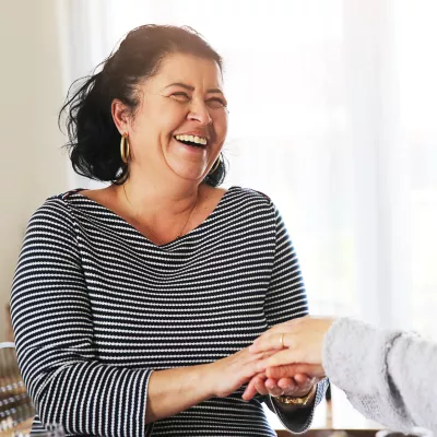 Two women, one holding another's hand, as she receives comfort from a friend after a cancer diagnosis.