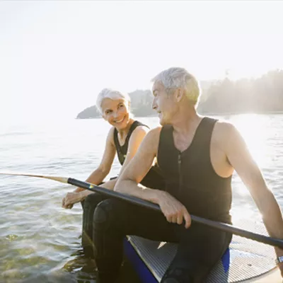 An older Caucasian couple takes the paddleboard on the lake.