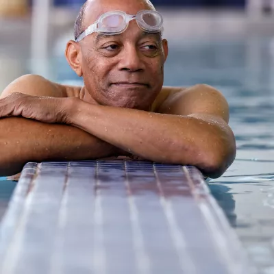 Elderly black man with goggles in a swiming pool.