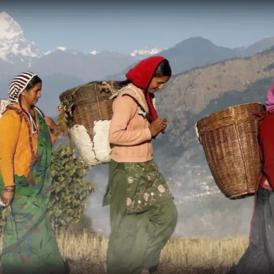 International women walking with baskets on their backs.