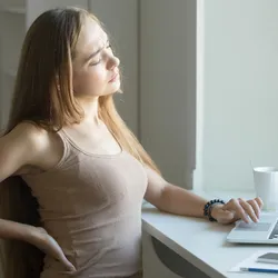 Woman sitting in a chair while experiencing back pain