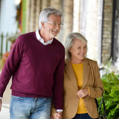 Elderly couple walking down a sidewalk window shopping.