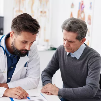 A doctor reviewing test results with a male patient at an appointment.