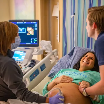 Masked doctor showing mom and dad an ultrasound of their baby