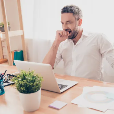 Man yawning while looking at laptop screen