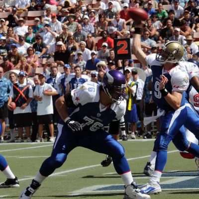 Football star, Drew Brees, passing the ball to a player.