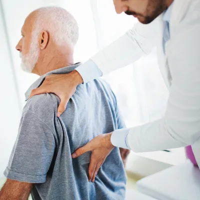 A doctor does a lower back exam on a patient. 