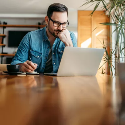 A gentleman indoors and focused on a task on his laptop