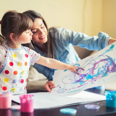 A mother and young daughter painting together. 