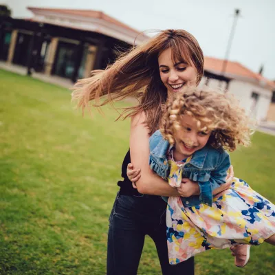 Mom spins her young daughter around in the grass