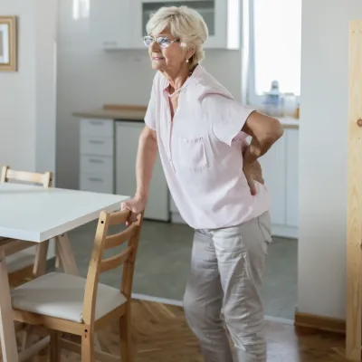 A woman experiencing lower back pain in her home. 
