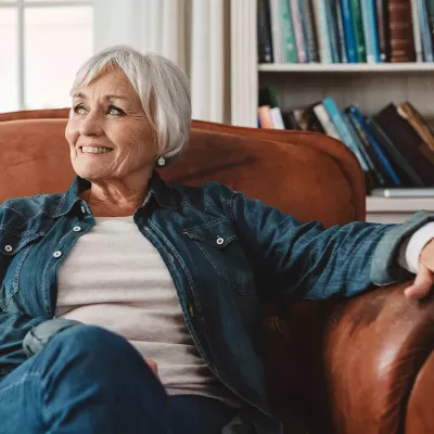 A senior woman sitting on a couch while at home.