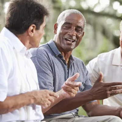 Three men have a conversation outdoors.
