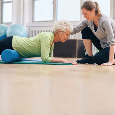 A woman uses a foam roller on her hip flexors.