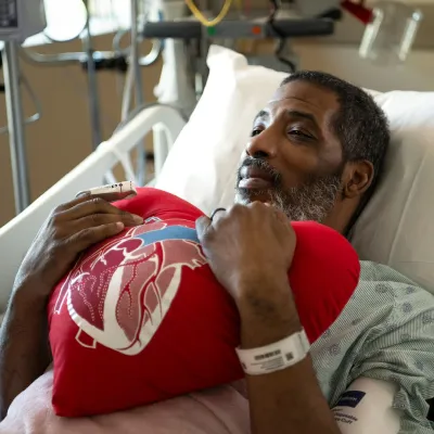 Patient holding heart shaped pillow in patient bed