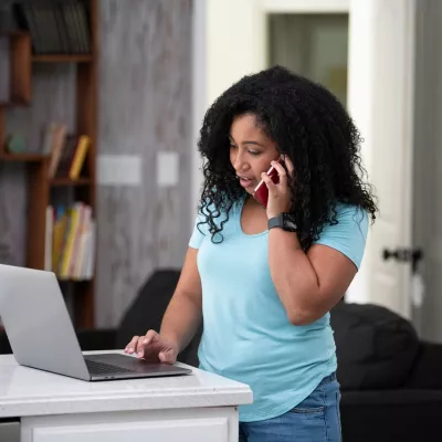 Woman on the phone while looking at her laptop.