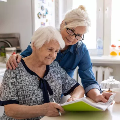 Woman with arm around mother looking at paperwork