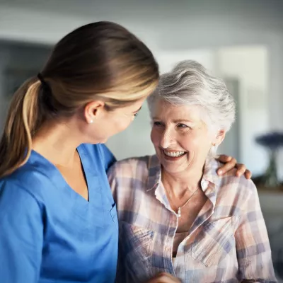 Nurse embracing senior woman at home