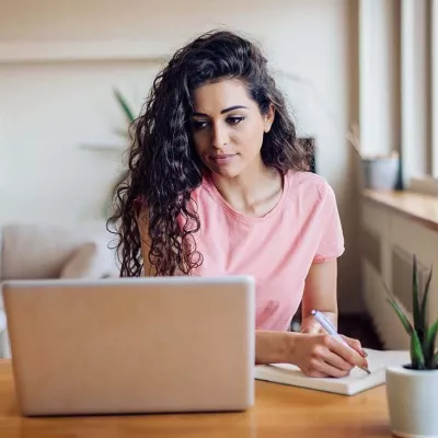 Young woman at table with laptop and notebook