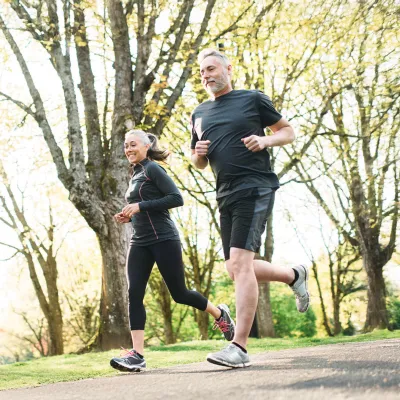 A Middle Aged Couple Jogs Through a Park
