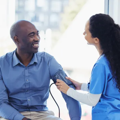 A male patient getting his blood pressure checked by a nurse.