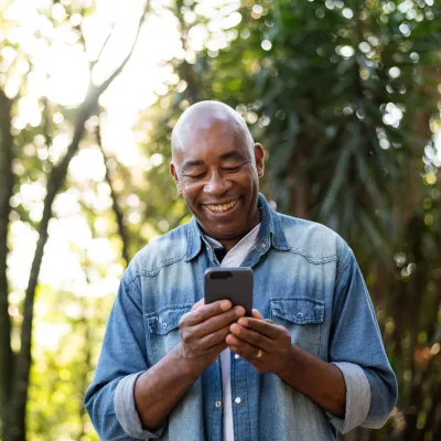 A man using a smartphone white outdoors.