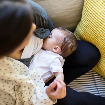 A mother breast-feeding her baby in the couch.