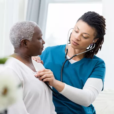 Nurse checking a woman patient's heartbeat.